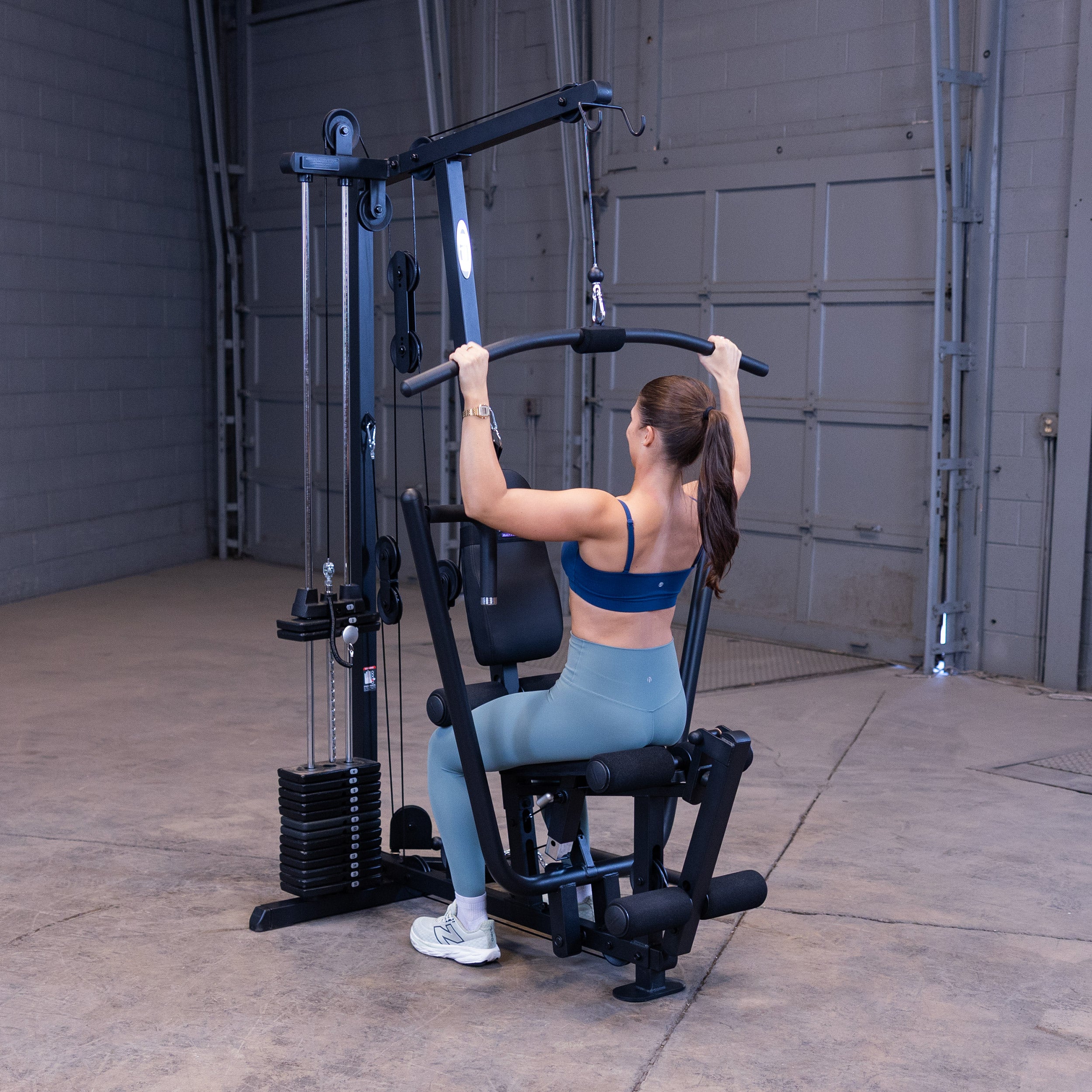 Person performing lat pulldowns on the Body-Solid G1B multi station home gym to strengthen the back and upper body