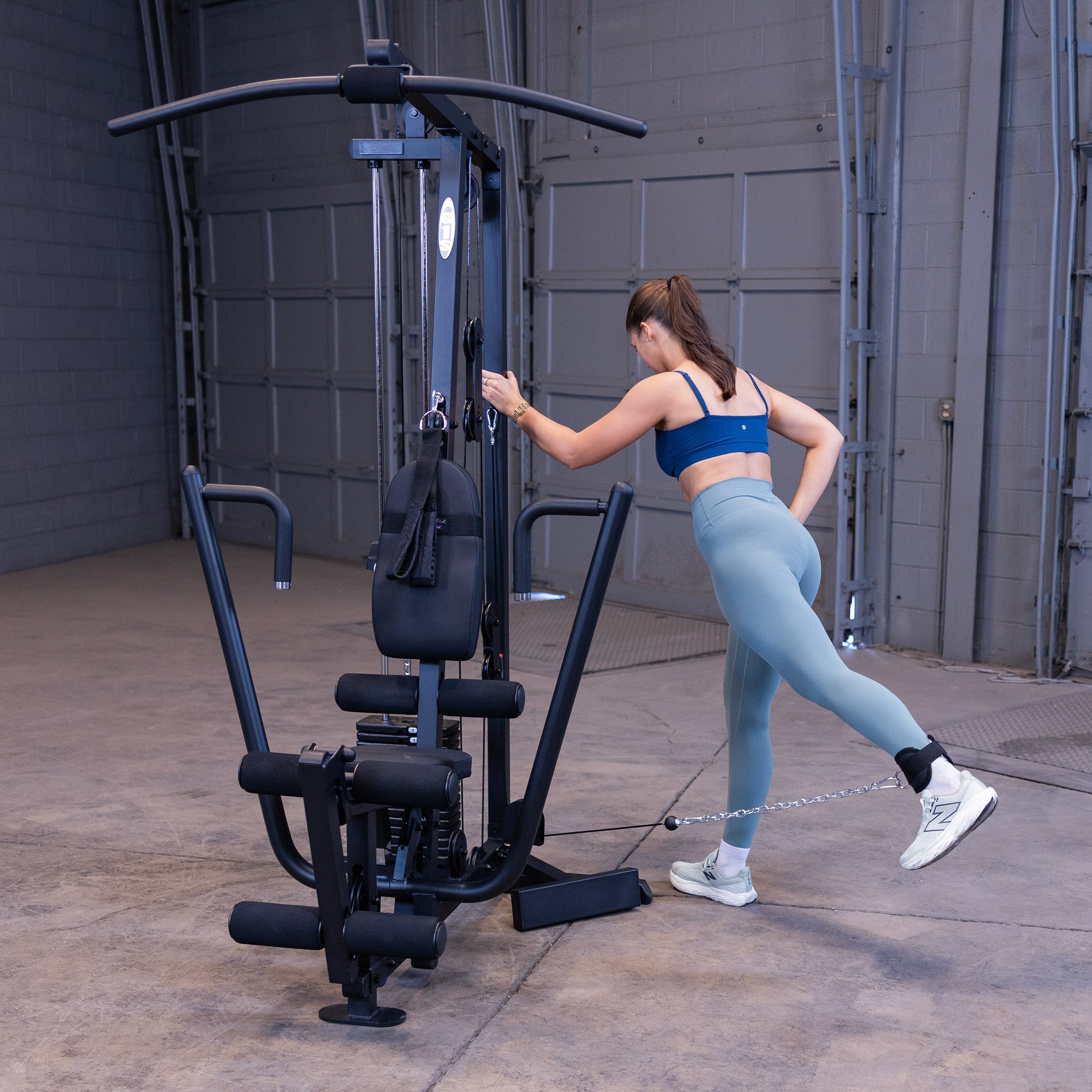 Person performing standing cable hip extensions on the Body-Solid G1B multi station home gym to strengthen the glutes and hamstrings