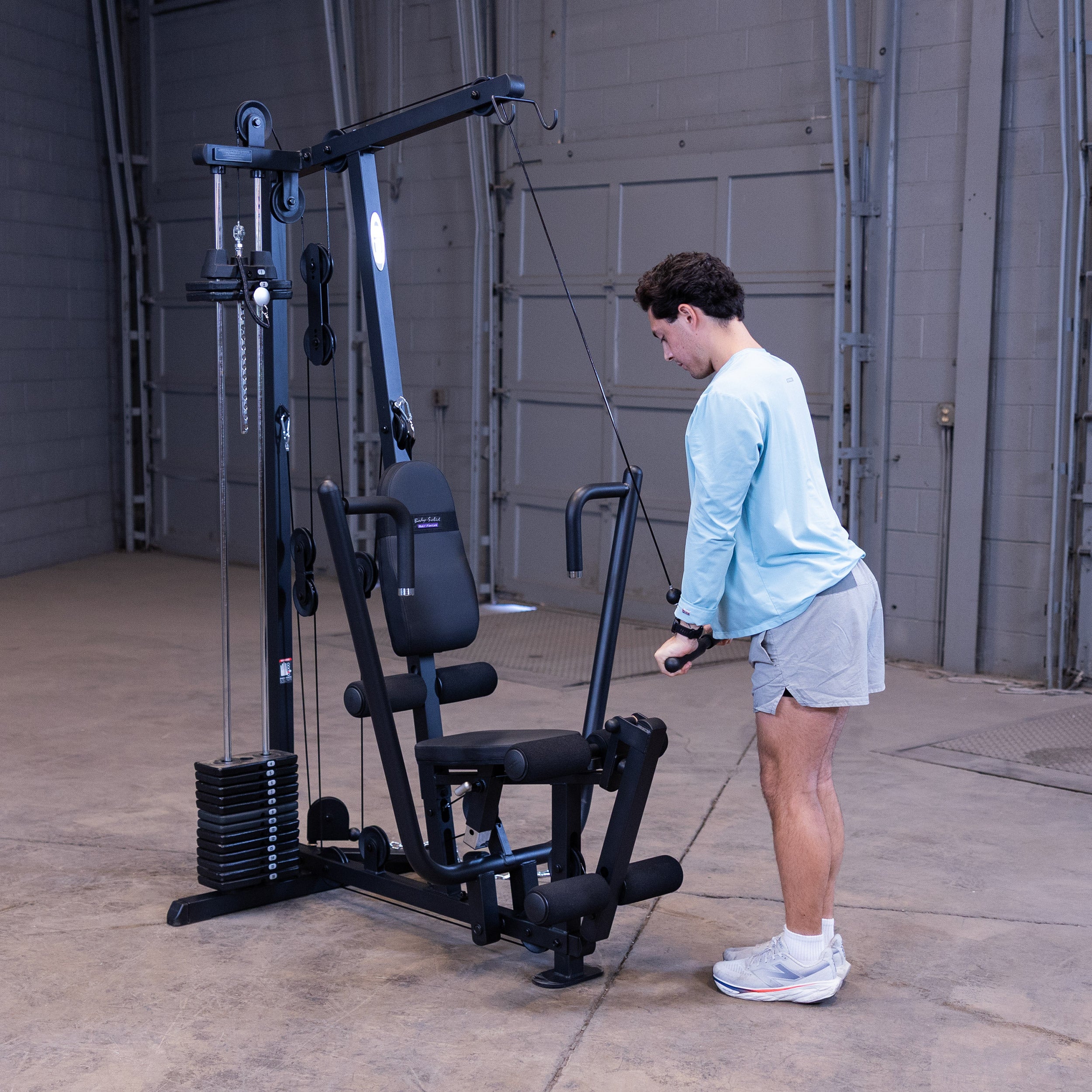 Person performing triceps pushdowns on the Body-Solid G1B multi station home gym to strengthen the triceps