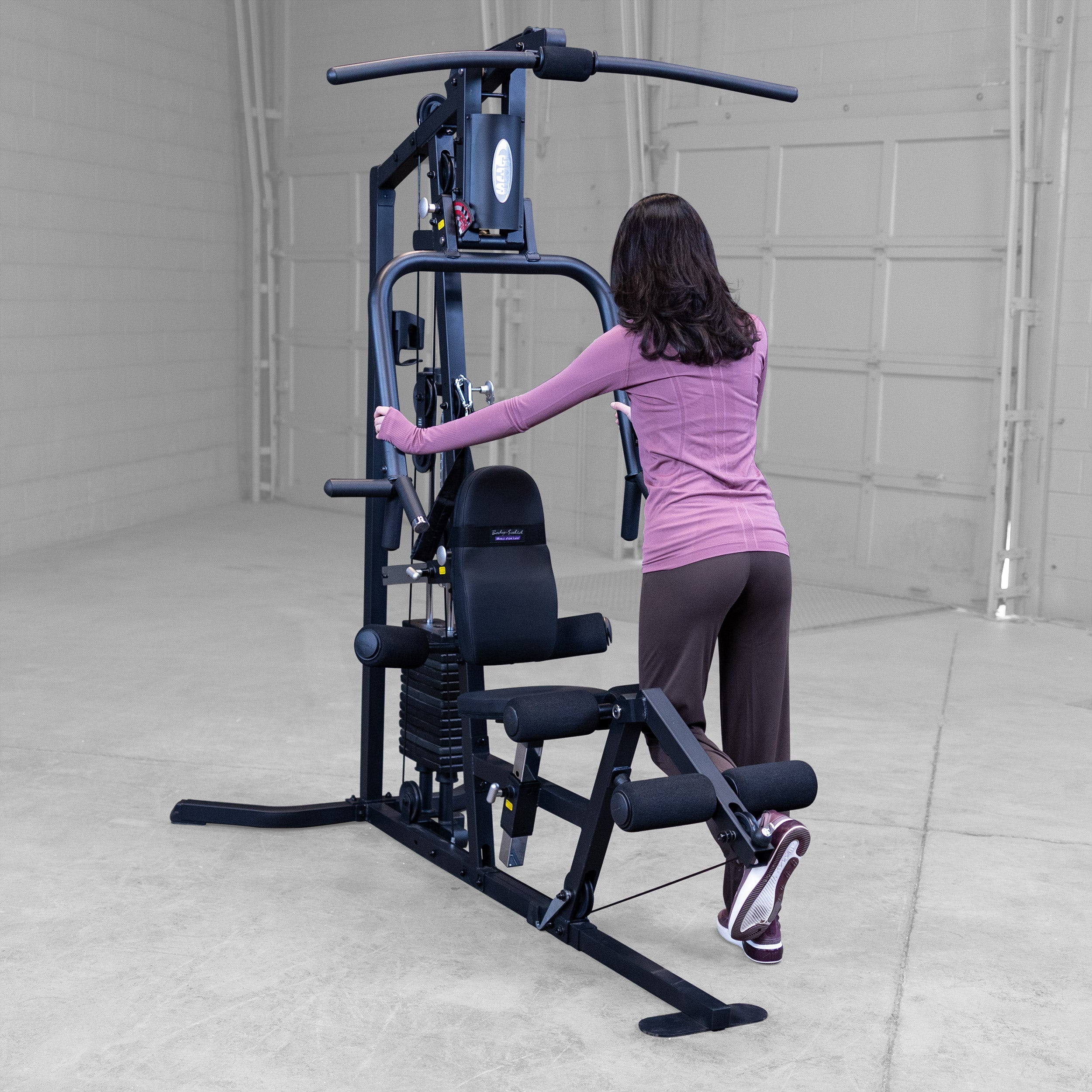 Person performing standing leg curls on the Body-Solid G3B multi station home gym to strengthen the hamstrings