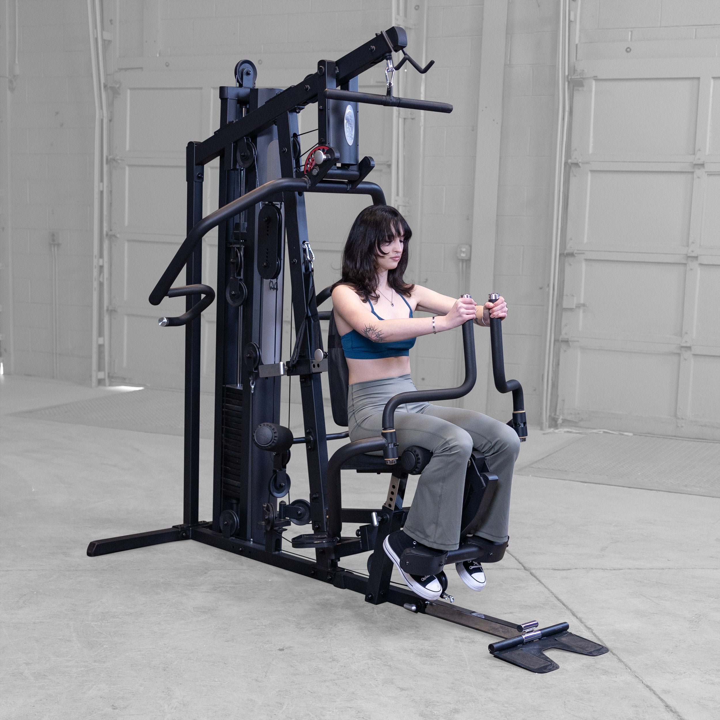 Person performing pec fly exercises on the Body-Solid G5B multi station home gym to strengthen the chest shoulders and upper body