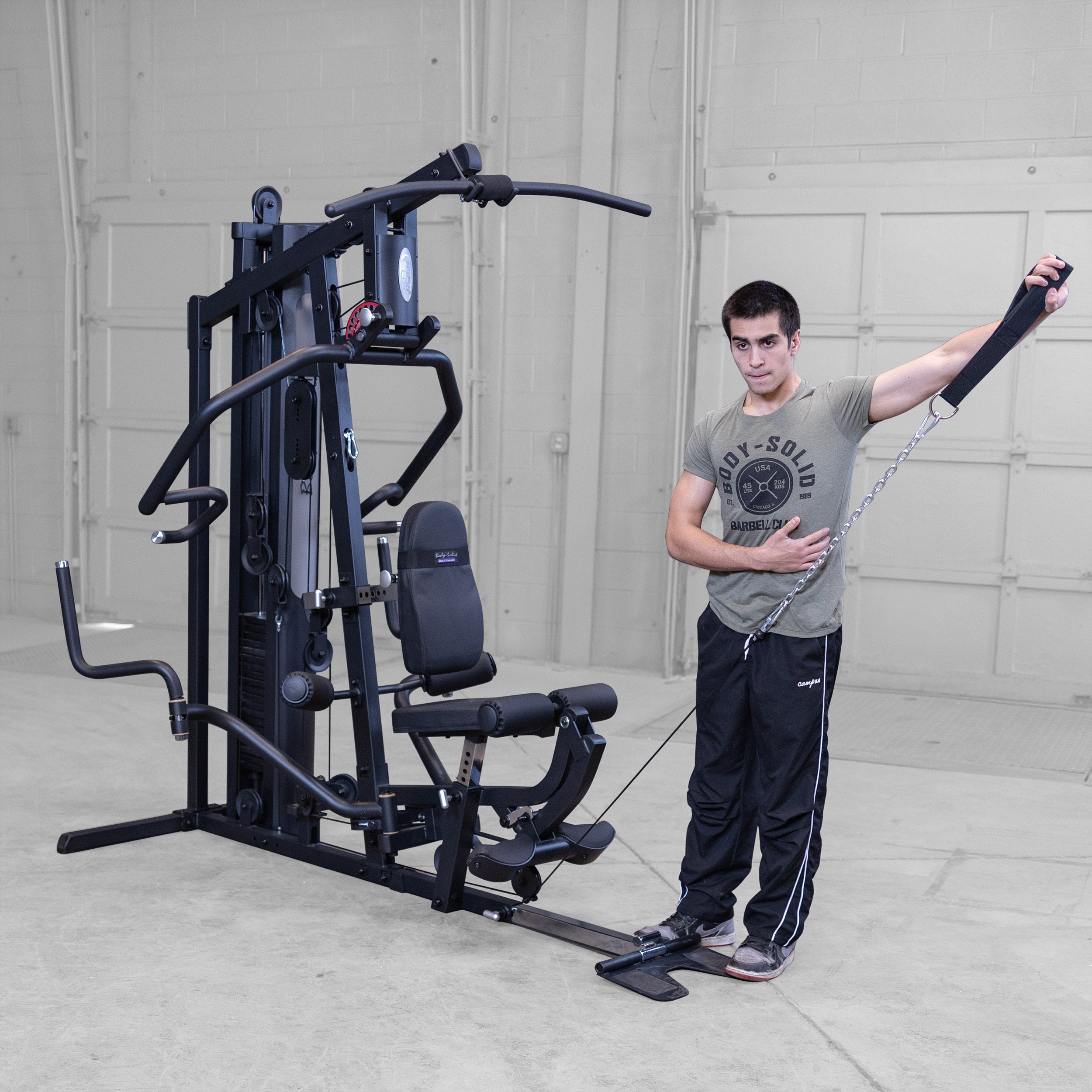 Person performing single arm cable lateral raises on the Body-Solid G5B multi station home gym to strengthen the shoulders and deltoids