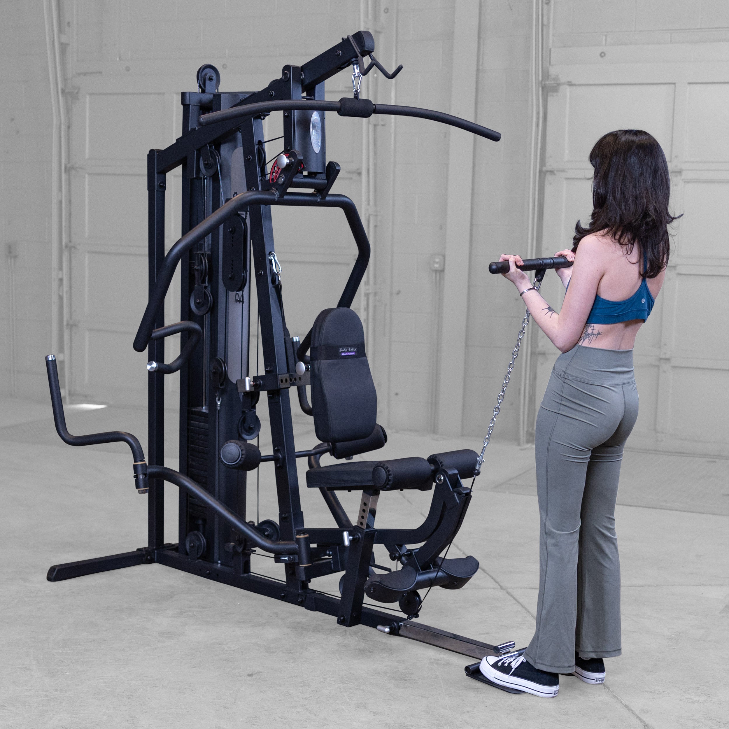 Person performing standing biceps curls on the Body-Solid G5B multi station home gym using the low cable attachment to strengthen the biceps and forearms