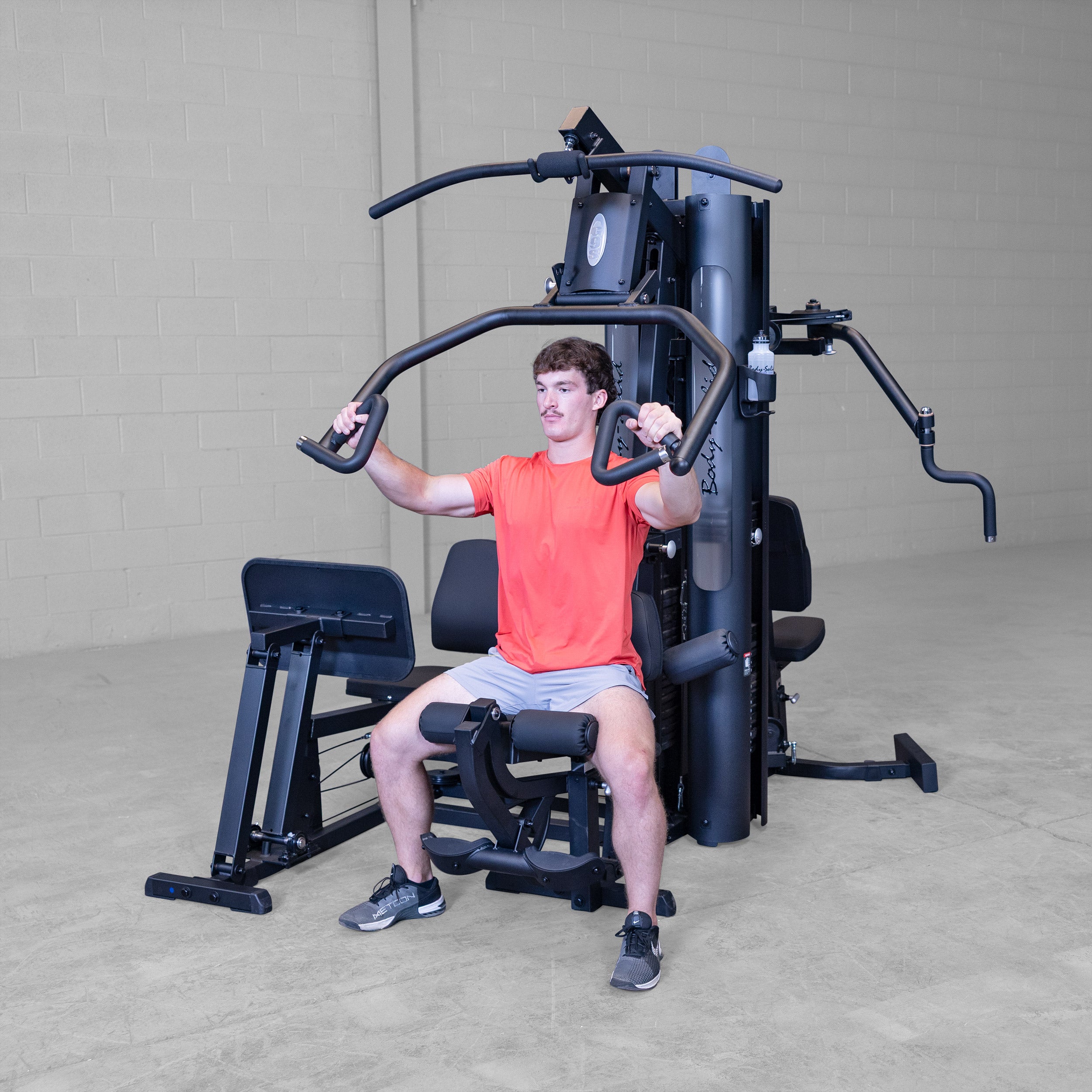 Person performing seated chest press exercise on the Body-Solid G9B dual stack multi station home gym using the Bi-Angular press arms