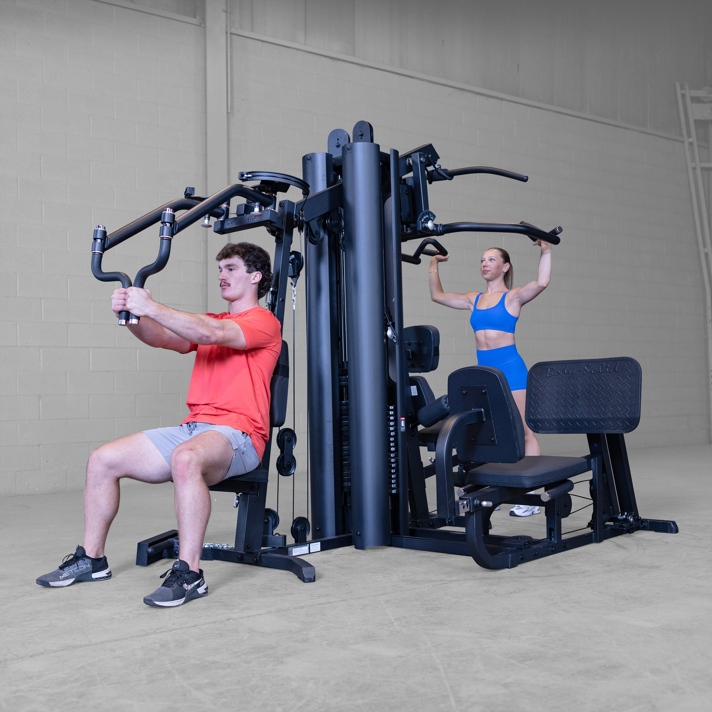 Two people performing chest press and shoulder press exercises simultaneously on the Body-Solid G9B dual stack multi station home gym