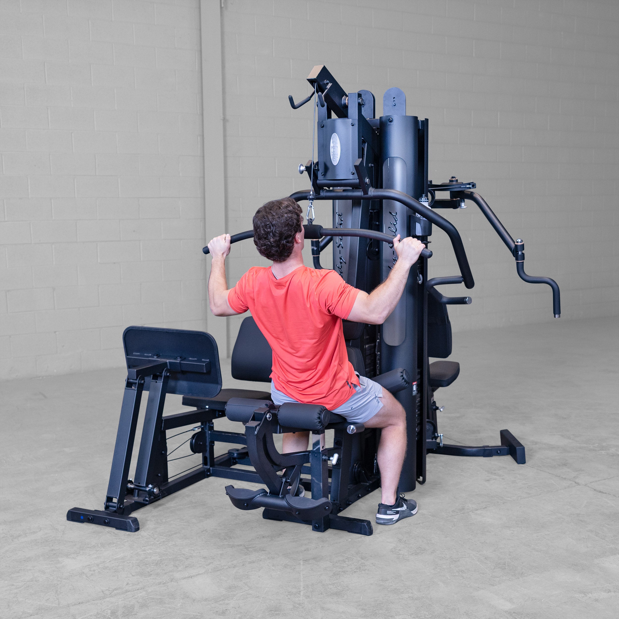 Person performing wide grip lat pulldown exercise on the Body-Solid G9B dual stack multi station home gym using the high pulley station