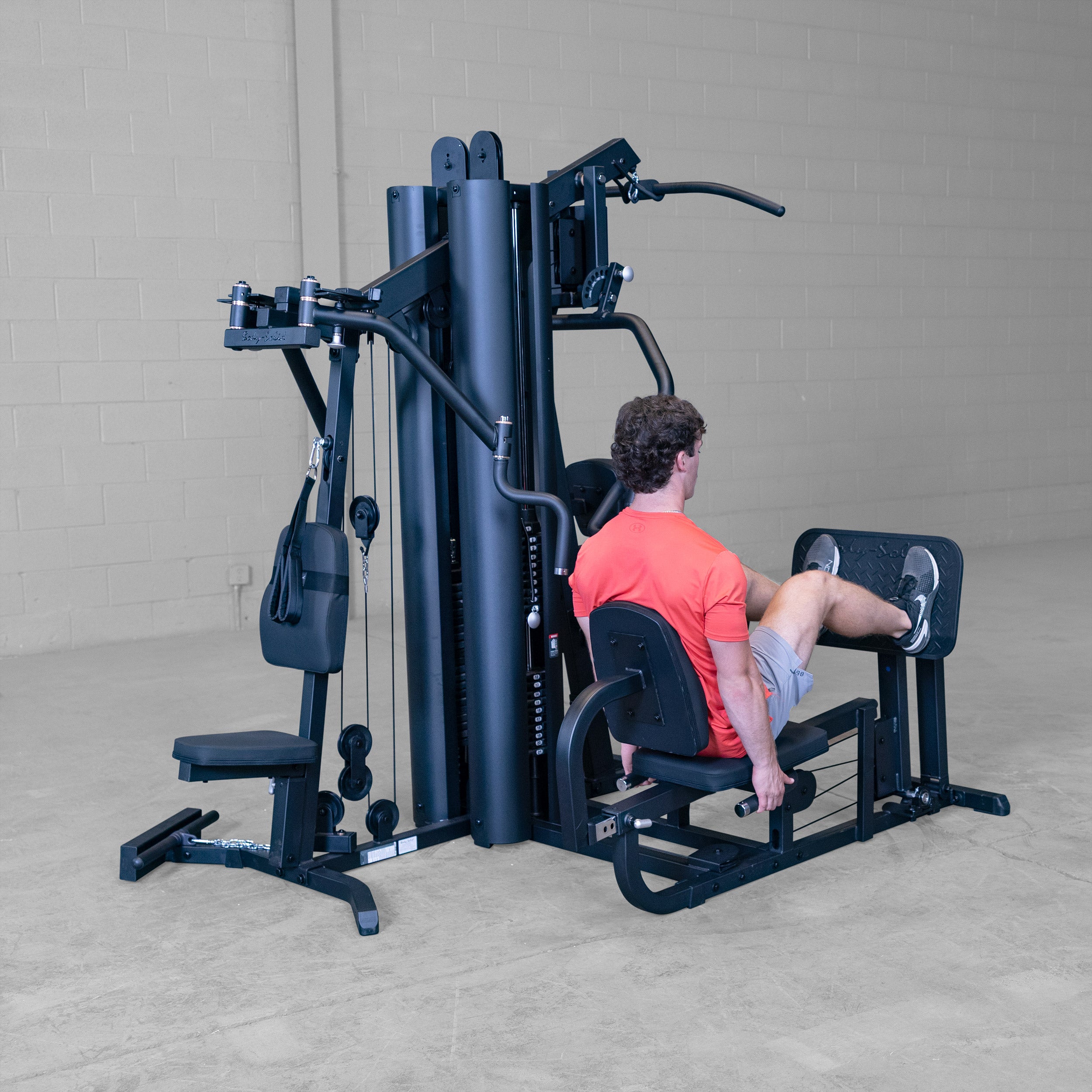 Person using the leg press station on the Body-Solid G9B dual stack multi station home gym performing a seated leg press exercise