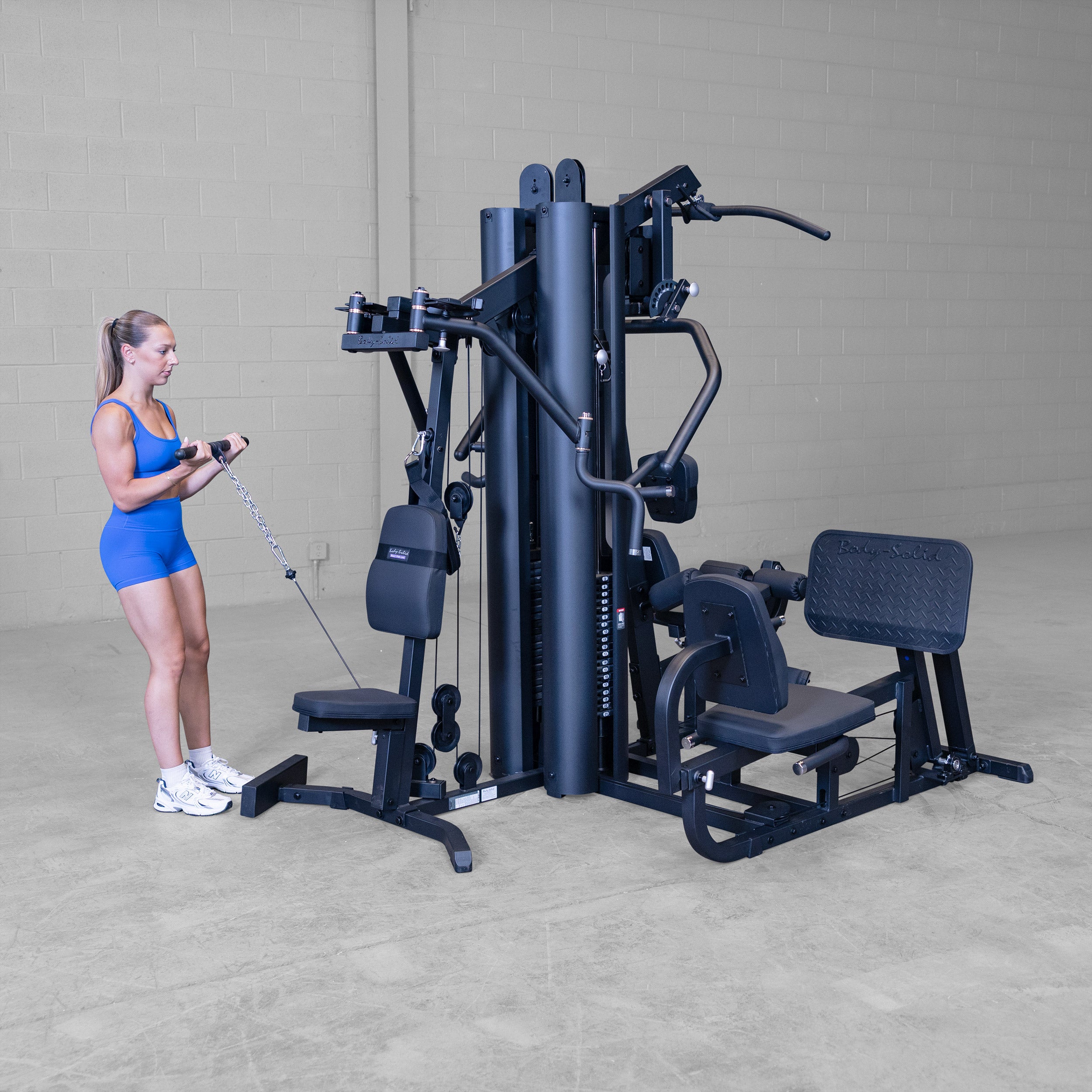 Person performing a standing cable biceps curl on the Body-Solid G9B dual stack multi station home gym using the low pulley attachment