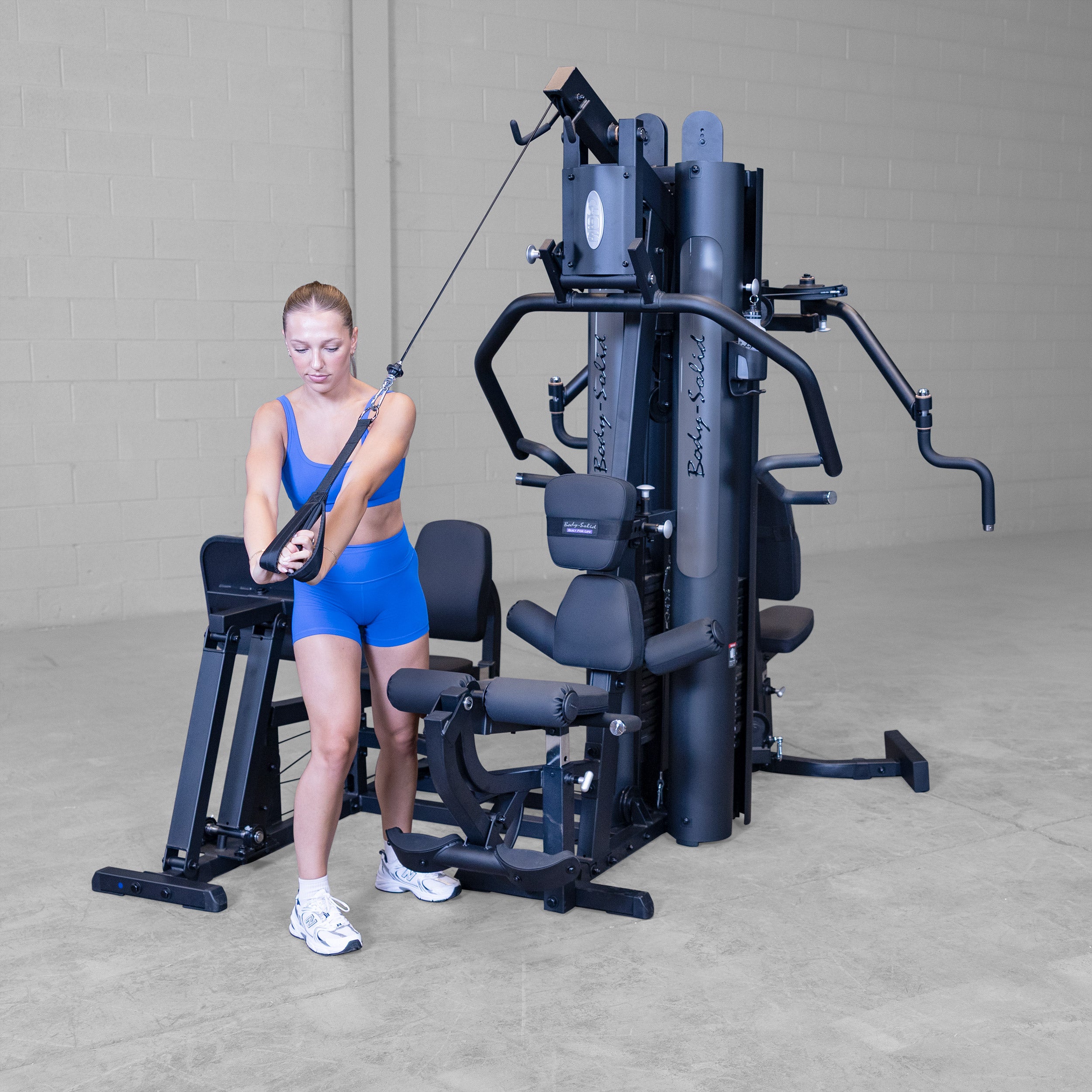 Person performing standing cable wood chop exercise on the Body-Solid G9B dual stack multi station home gym using the high pulley cable attachment