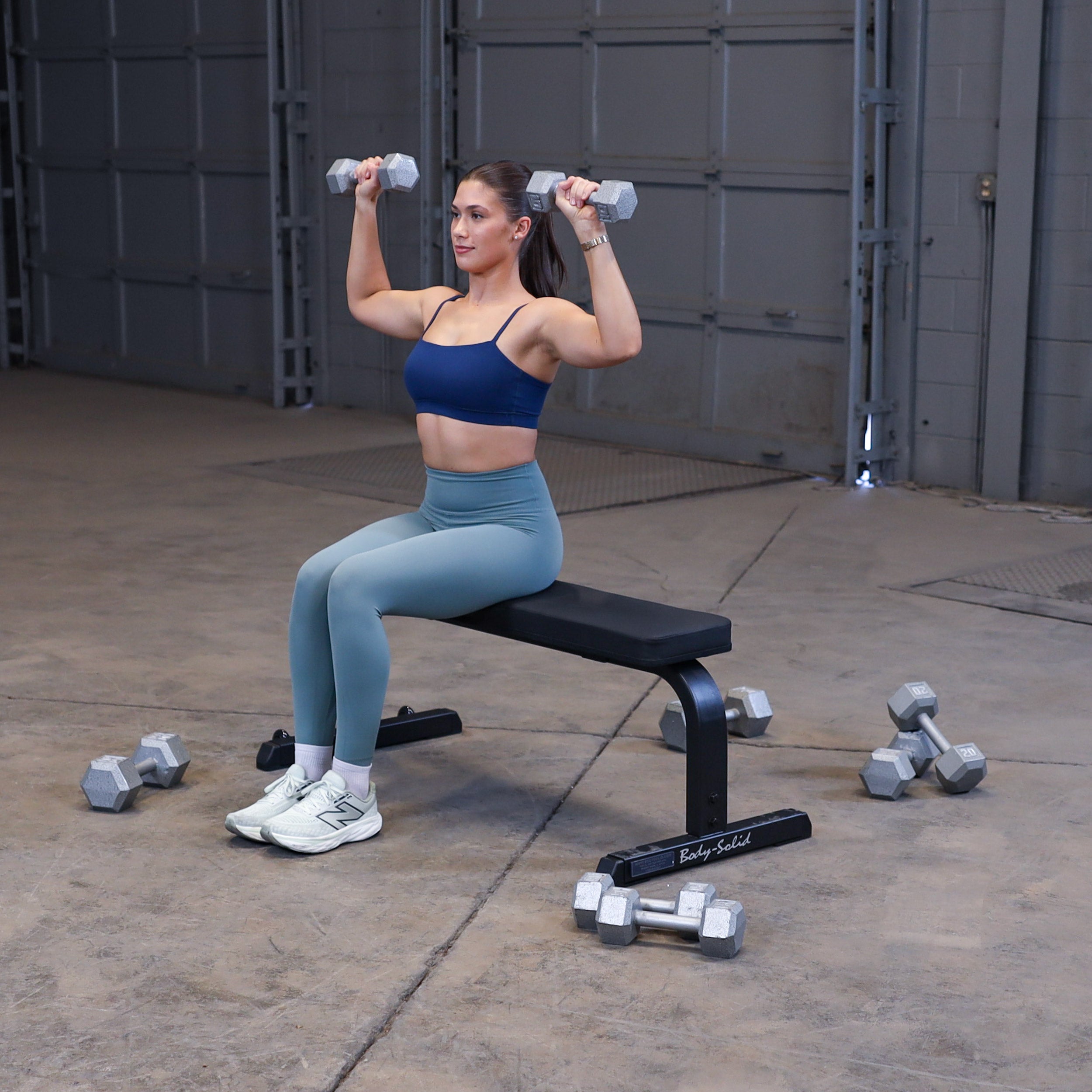 Person performing seated dumbbell shoulder press on the Body-Solid GFB350B flat bench