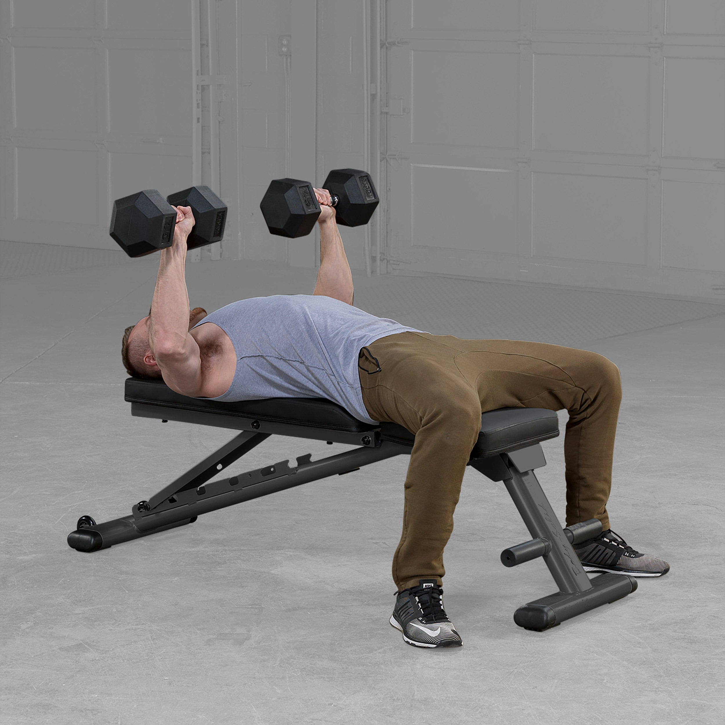 Person performing flat dumbbell bench press on Body Solid GFID225B folding adjustable weight bench in a home gym
