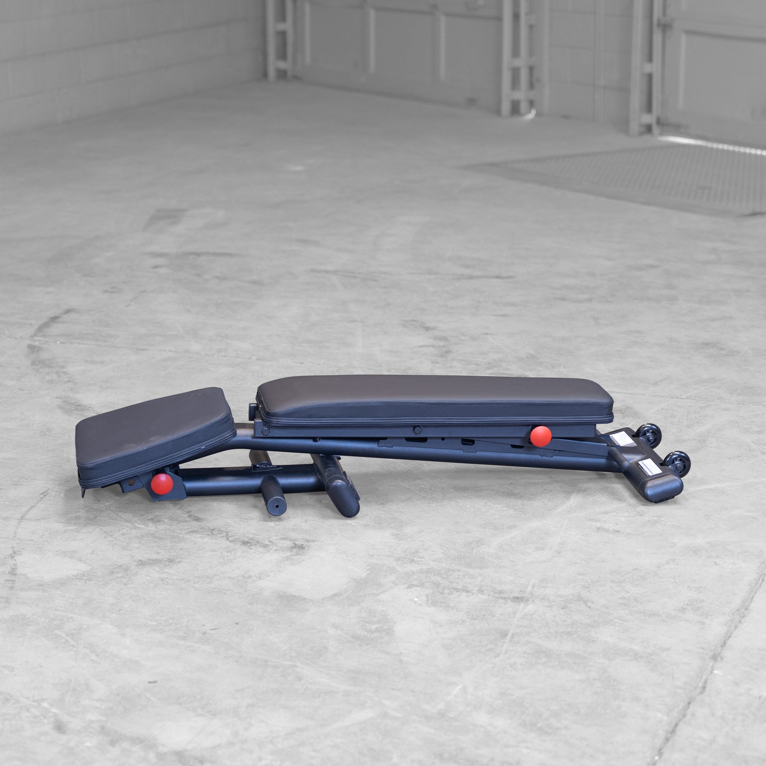 Body Solid GFID225B folding adjustable weight bench shown folded for compact storage in a home gym