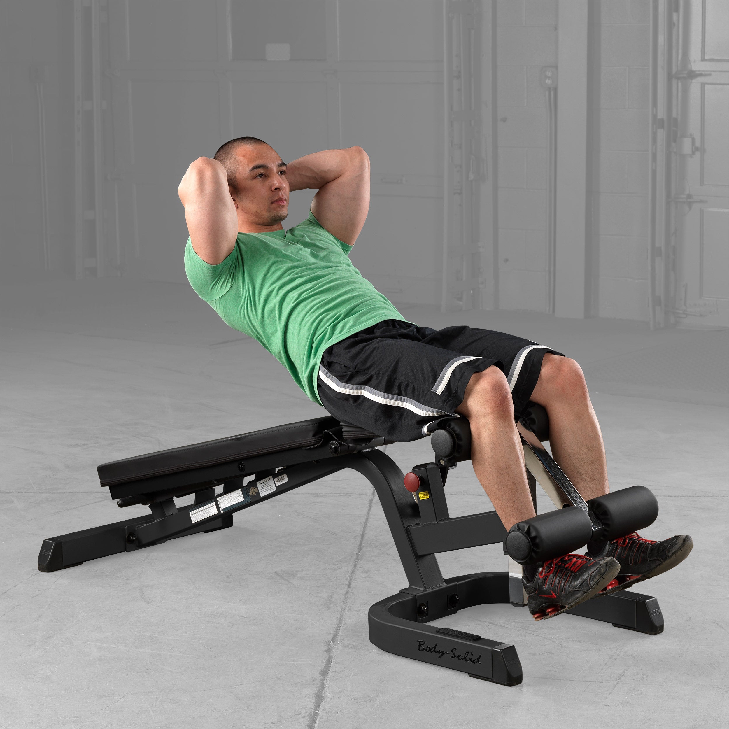 Body-Solid GFID71B Heavy Duty Flat Incline Decline Bench being used for decline sit-ups with the adjustable leg hold-down attachment providing secure lower body support