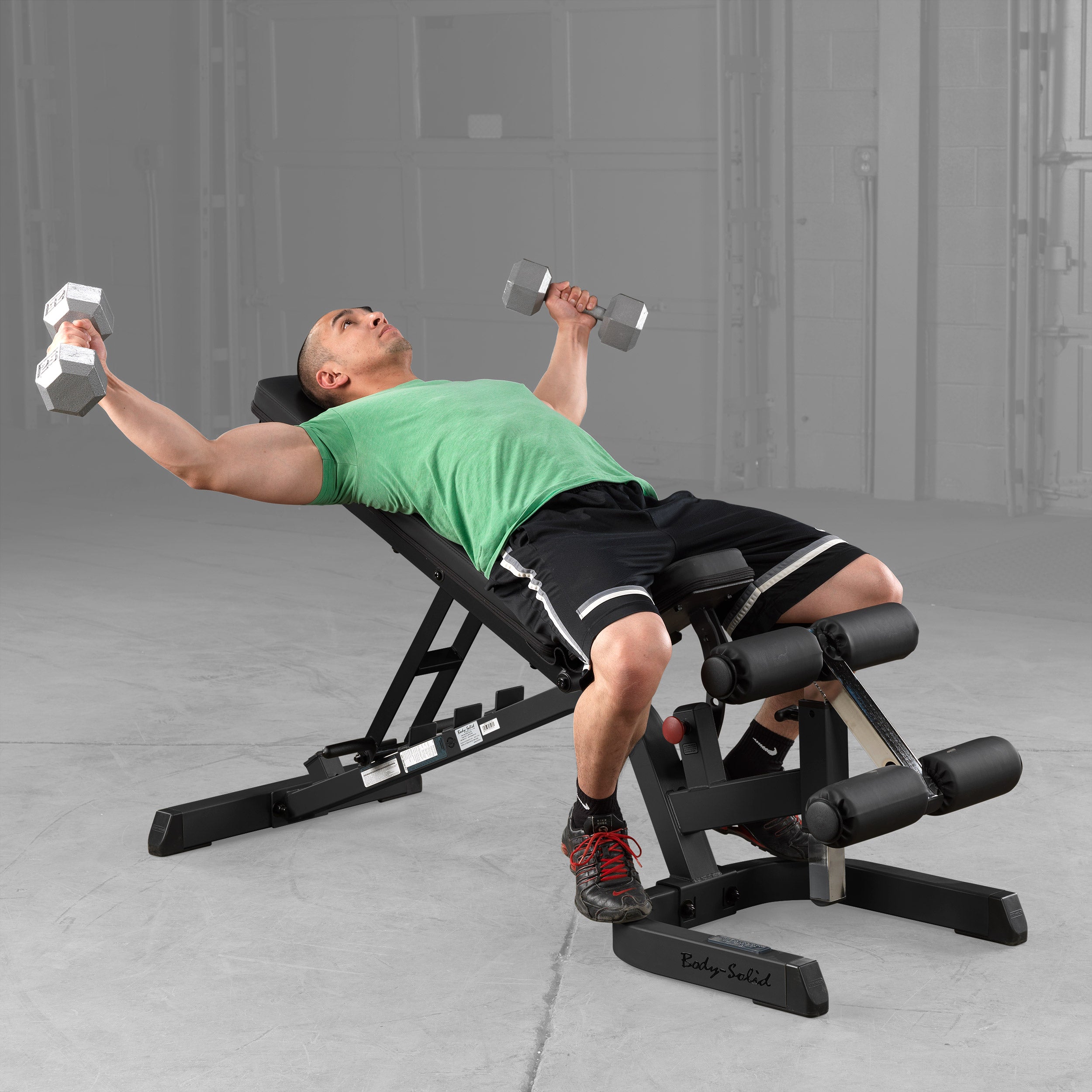 Body-Solid GFID71B Heavy Duty Flat Incline Decline Bench being used for incline dumbbell fly exercises, demonstrating the adjustable incline back pad, secure leg hold-down attachment, and stable commercial-grade steel frame for upper chest training