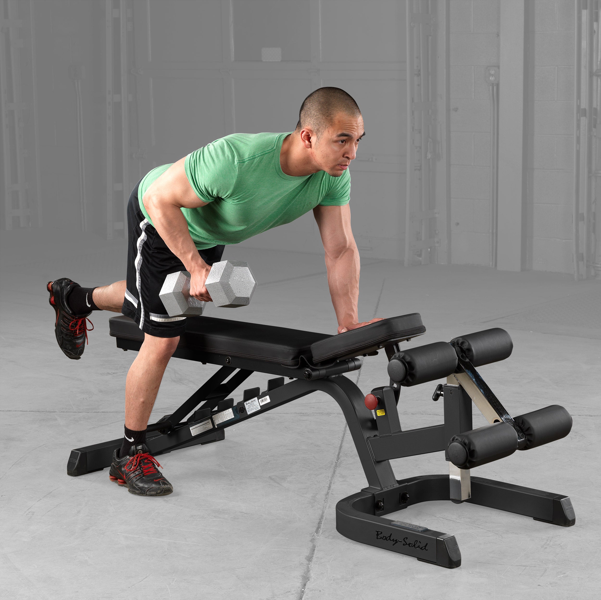 Body-Solid GFID71B Heavy Duty Flat Incline Decline Bench being used for one-arm dumbbell rows, demonstrating the adjustable flat bench position, commercial-grade steel construction, and stable platform for effective back and upper body strength training