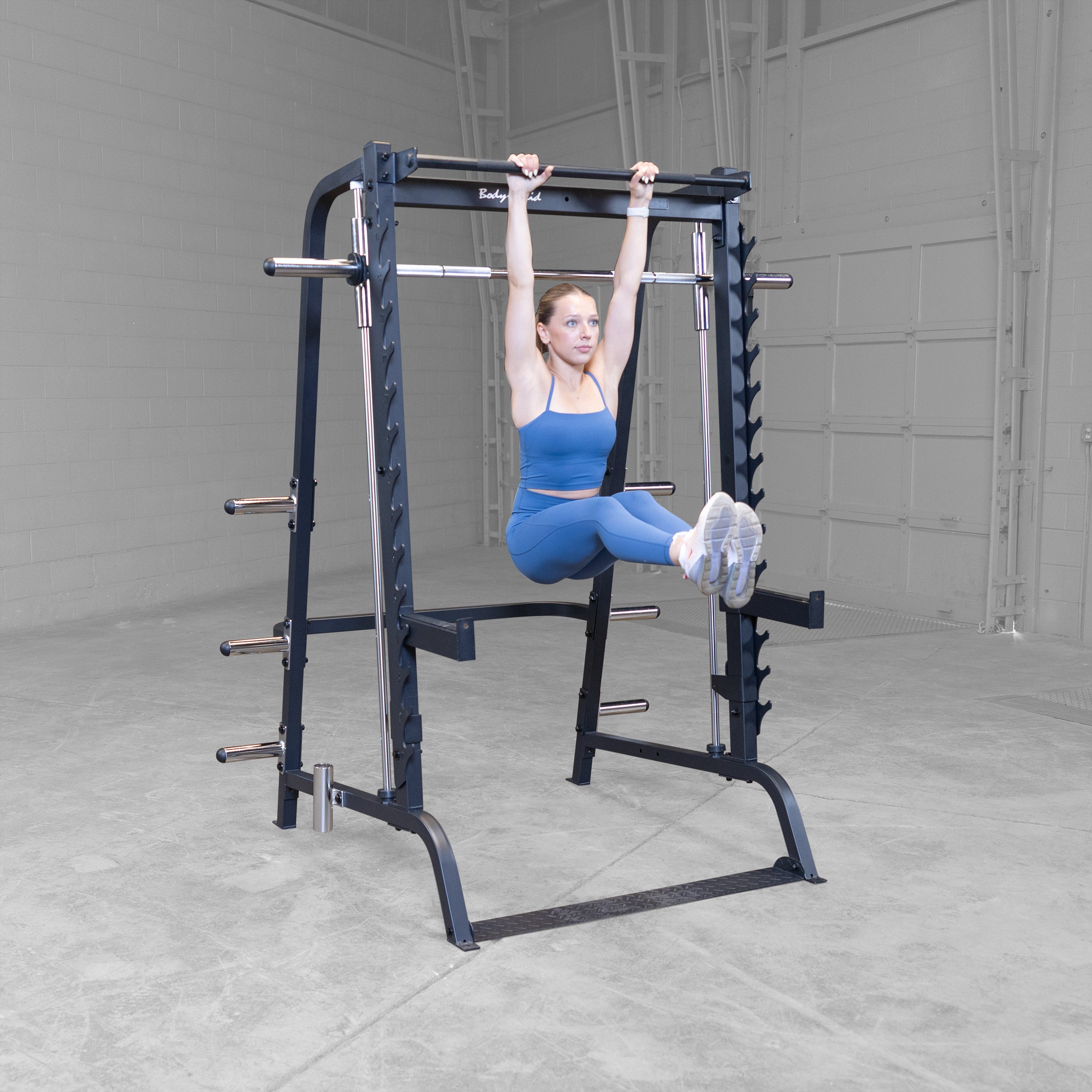 Athlete performing hanging leg raises on the pull up bar of the Body-Solid GS348B Series 7 Smith Machine targeting the core and abdominal muscles