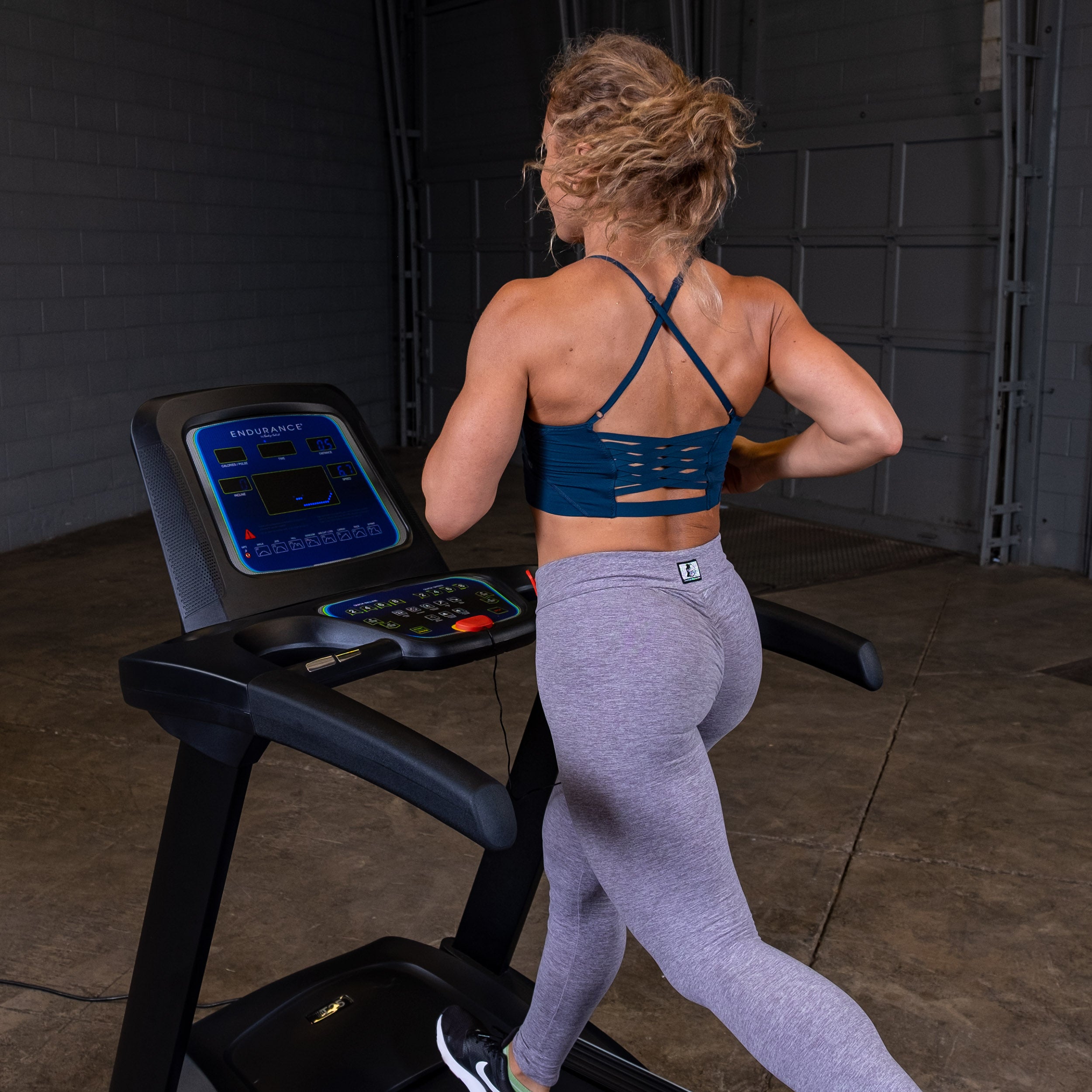 Woman running on Body-Solid Endurance T25 treadmill during home cardio workout