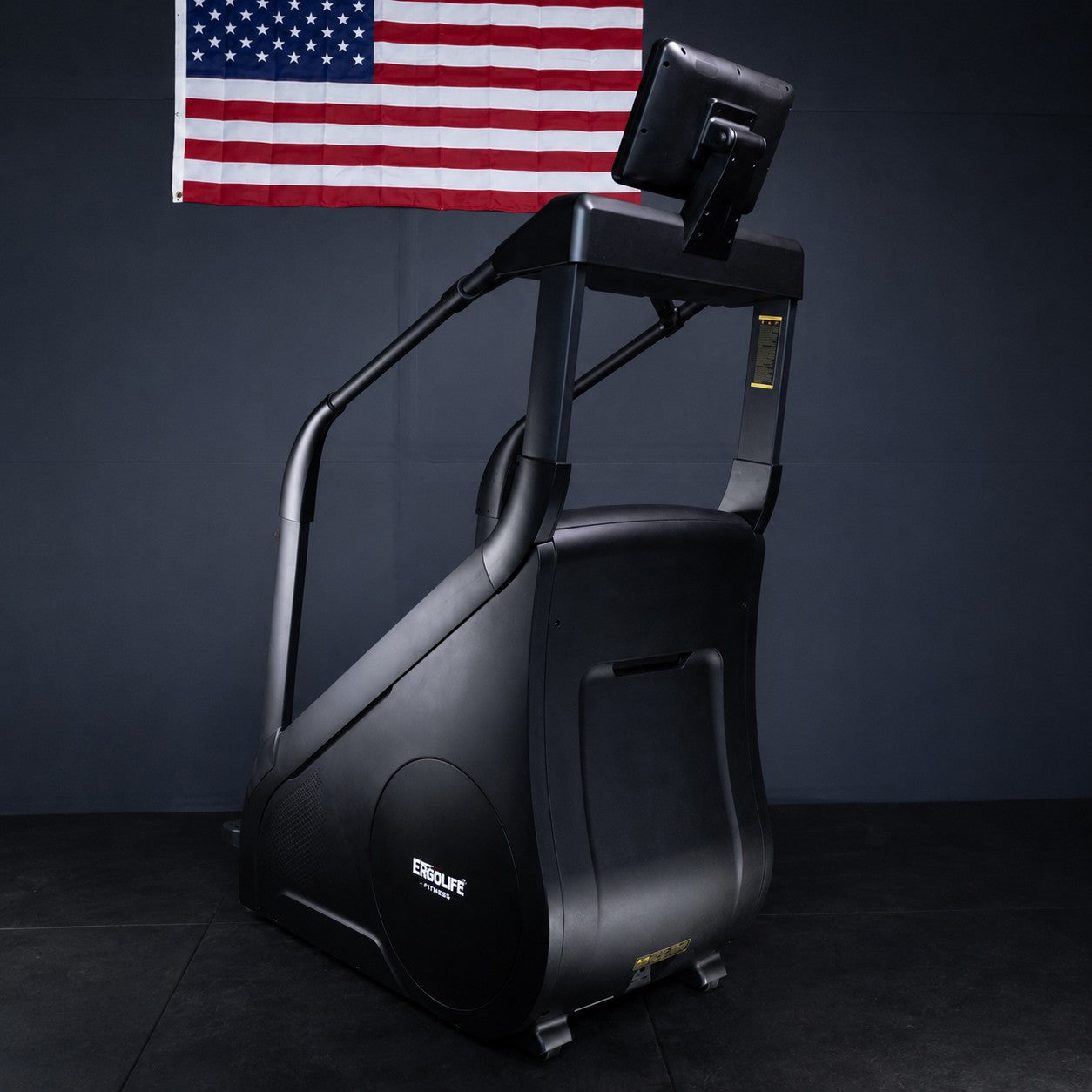 ERGOLIFE CS201ES adjustable resistance stair climber shown from the rear angle with touchscreen display in a gym environment