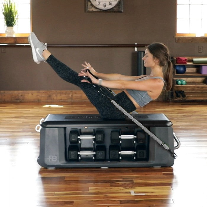 Woman performing resistance band core exercise on FITBENCH FREE adjustable workout bench
