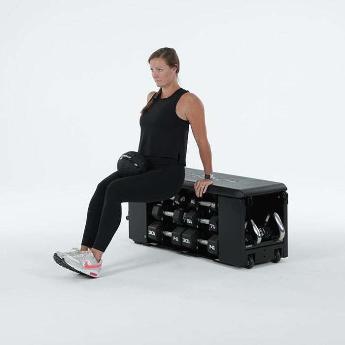 Woman performing triceps dip exercise on FITBENCH One NXT Gen workout bench with slam ball