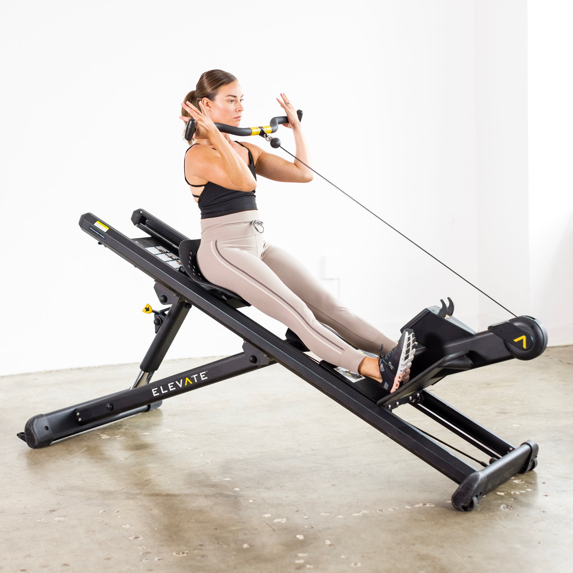 Person performing a bicep curl exercise on the Total Gym ELEVATE Row ADJ adjustable incline rowing machine to strengthen the biceps and upper body