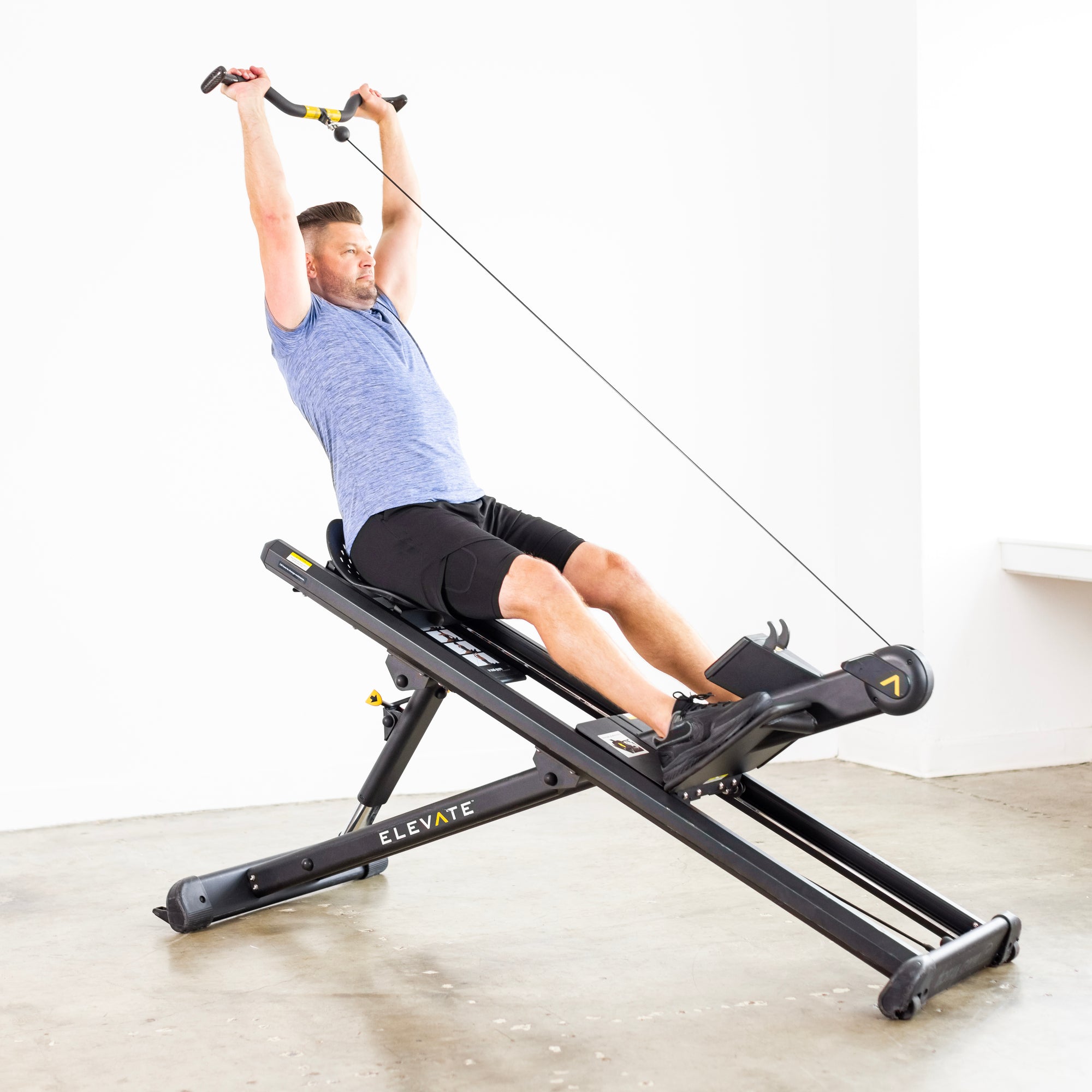 Person performing an overhead shoulder press on the Total Gym ELEVATE Row ADJ adjustable incline rowing machine to strengthen the shoulders and upper body