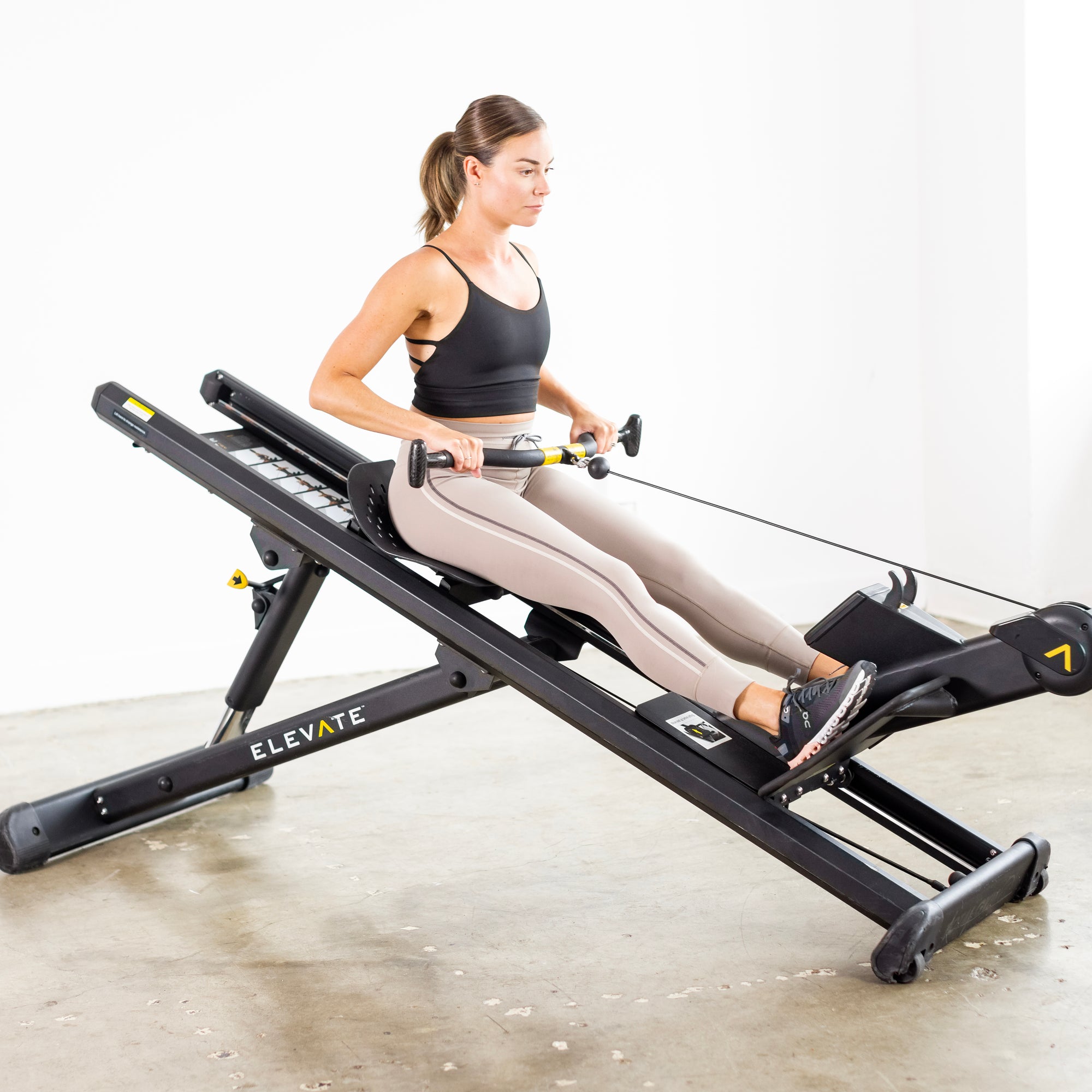 Person performing a seated row exercise on the Total Gym ELEVATE Row ADJ adjustable incline rowing machine to build upper body and back strength