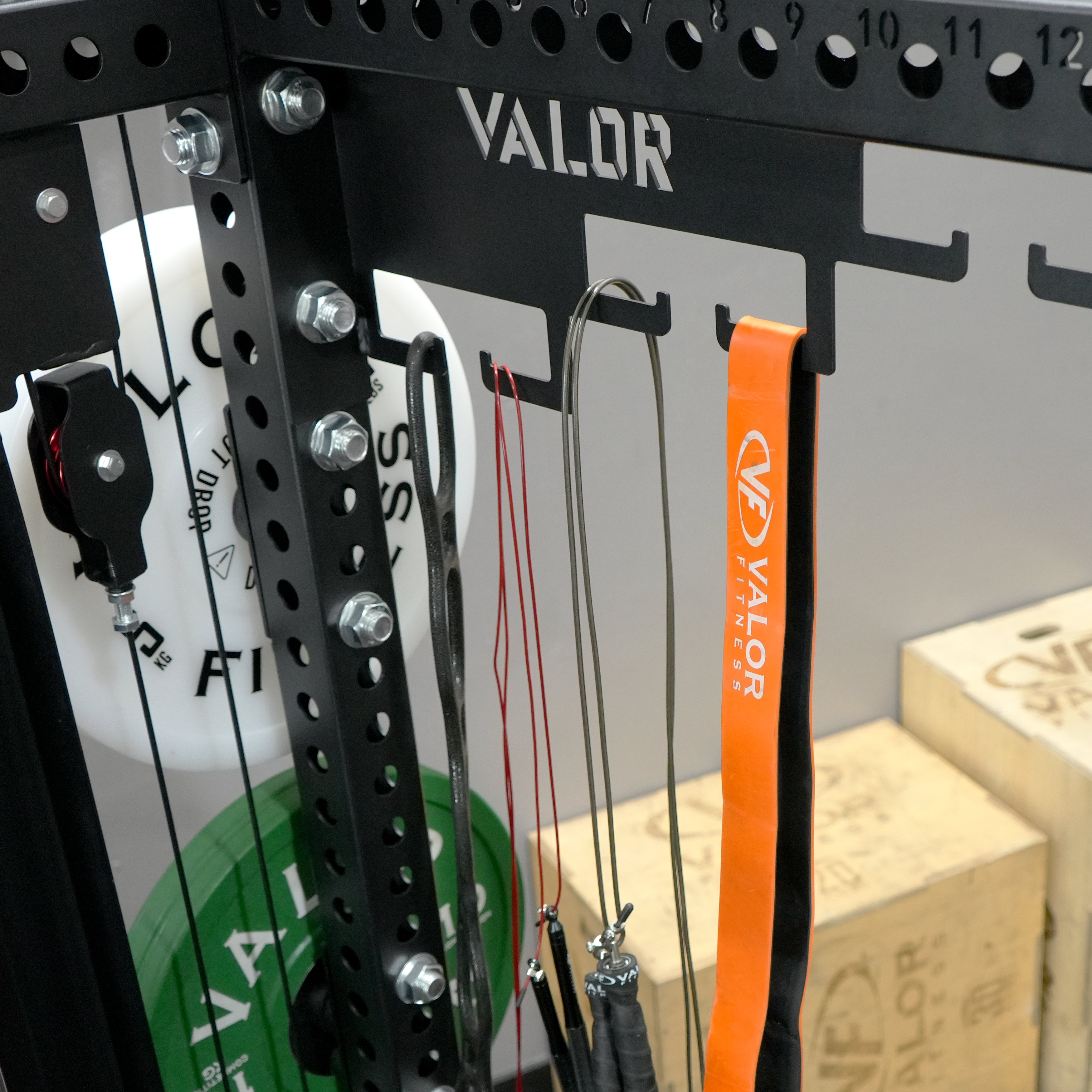 Close up view of the Valor Fitness BD-83 integrated accessory storage hooks holding resistance bands and cable attachments