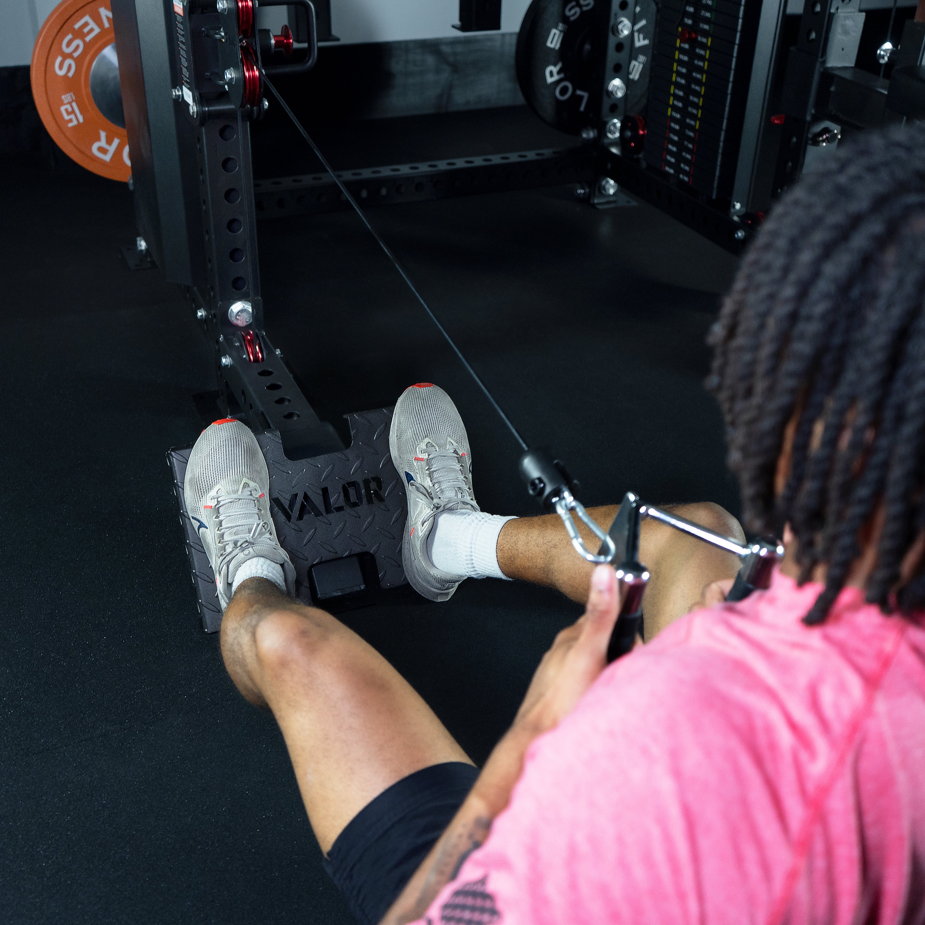 Athlete performing seated low row exercise on the Valor Fitness BD-83 functional trainer using low row footplate attachment and cable handle