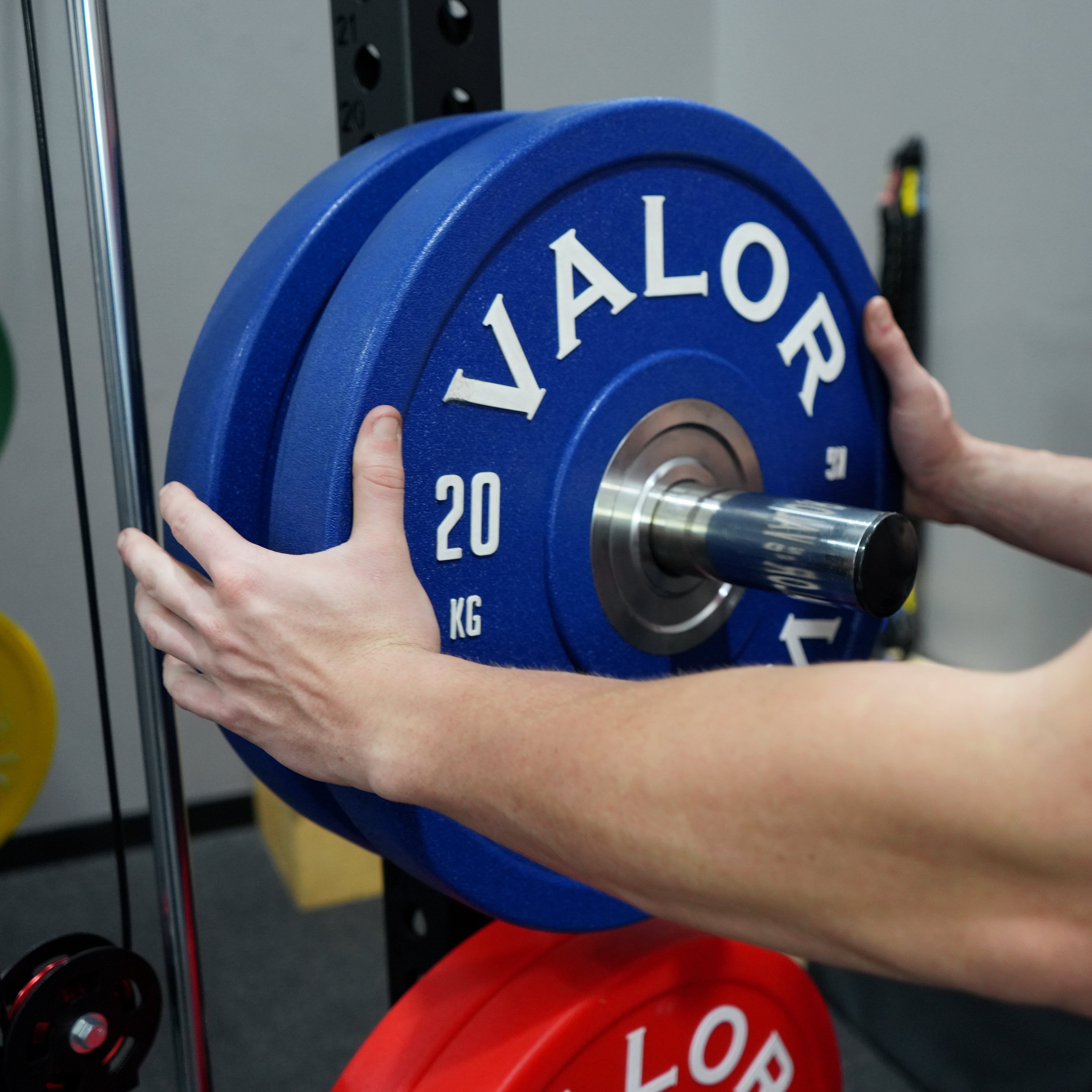 Close up view of the Valor Fitness BD-83 Olympic weight plate storage pegs with bumper plates mounted on the power rack frame