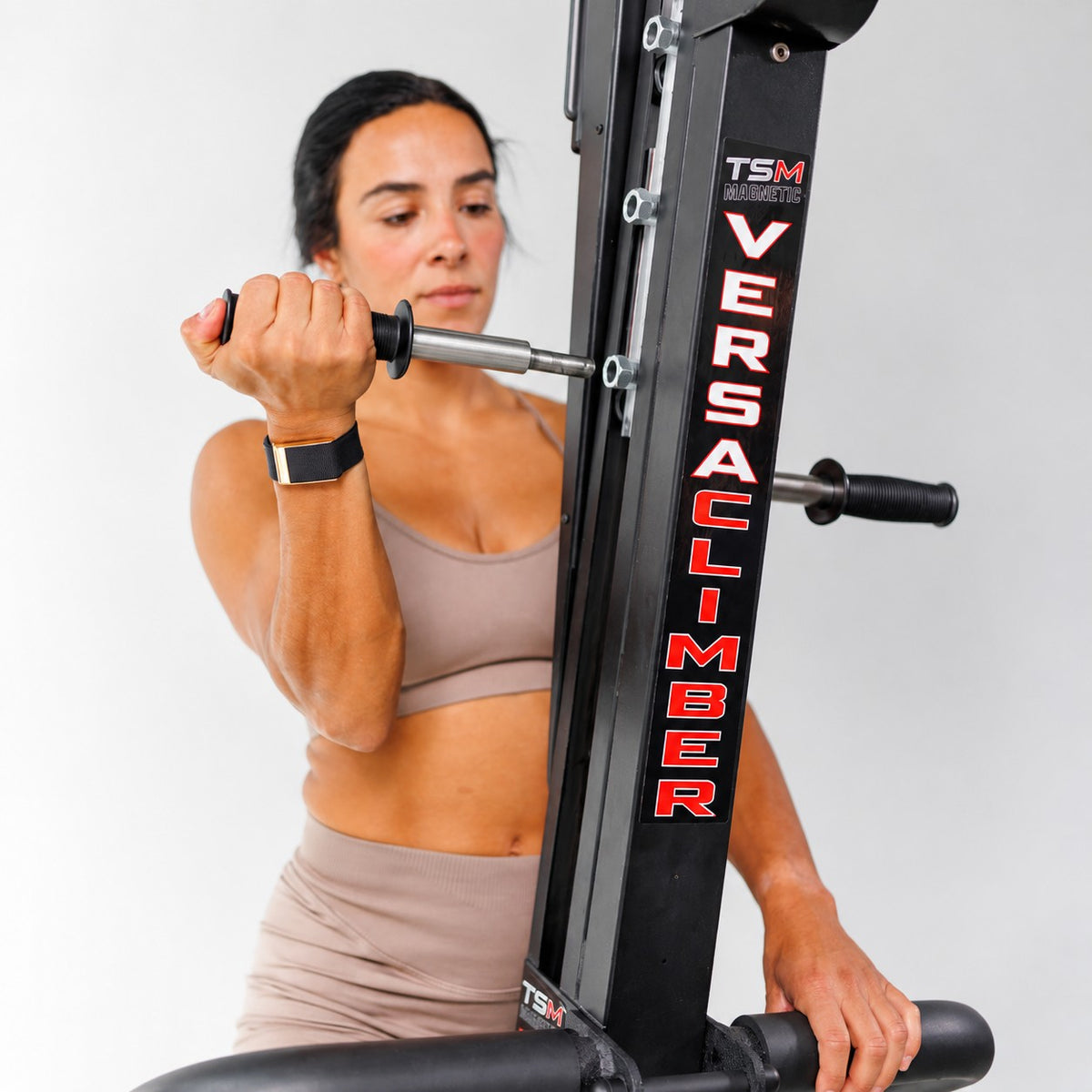 Woman gripping the adjustable handles of the VersaClimber TS-Magnetic vertical climber during an upper-body workout